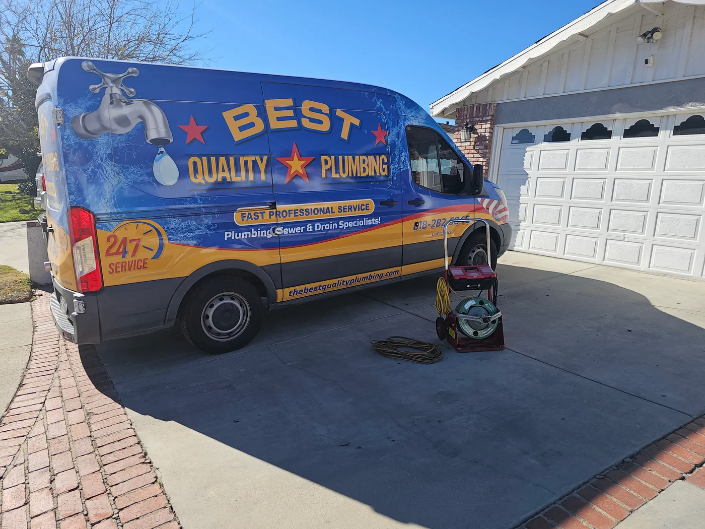 Best Quality Plumbing Services blue and gold service van parked at a home